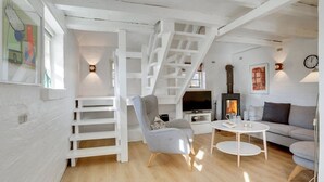Ein modernes Wohnzimmer mit Treppe, Kamin, Fernseher und einer gemütlichen Sitzecke.
