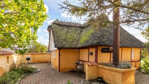 Ein traditionelles Haus mit einem Reetdach und einem Ziegelweg, der davorführt.