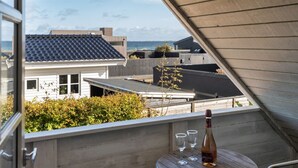 Ein Balkon mit Tisch, zwei Gläsern und einer Weinflasche.