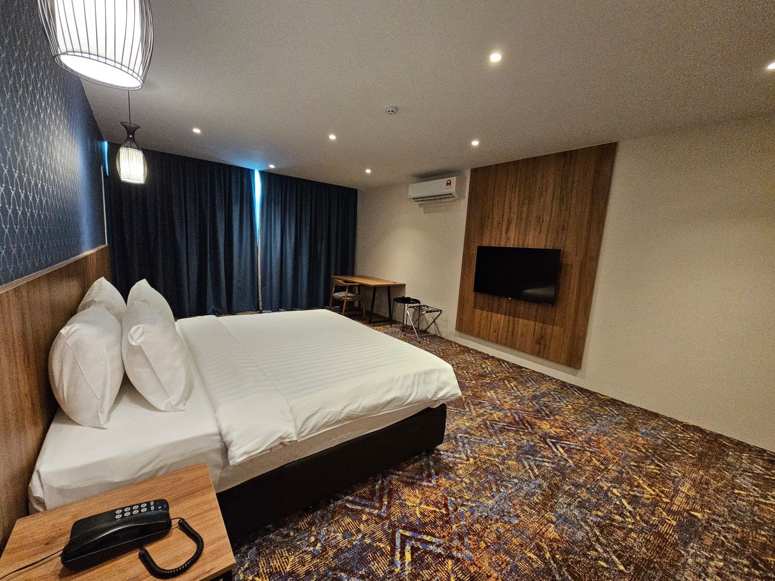 A hotel room with a bed, a desk, a chair, a TV, and a telephone.