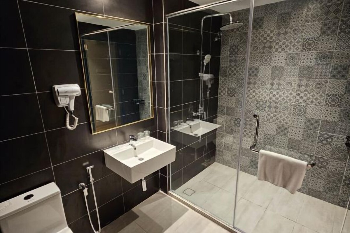 A modern bathroom with a glass-enclosed shower, a white sink, and a towel rack.