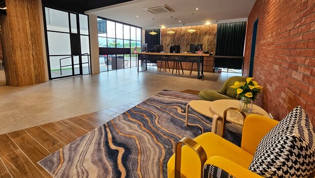 A modern hotel lobby with a reception desk, seating area, and large windows offering a view of the outdoors. - Le'genda Hotel (Kajang)