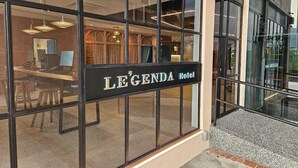 The exterior of the LEGENDA Hotel with large glass windows, a signboard, and a visible interior with a desk and chairs. - Le'genda Hotel (Kajang)