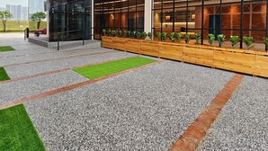 A modern building with a mix of glass and brick facades, a covered outdoor area with artificial grass, and a row of potted plants along the walkway. - Le'genda Hotel (Kajang)