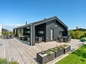 Een modern huis met een terras, buitenmeubels en een barbecuehoek.