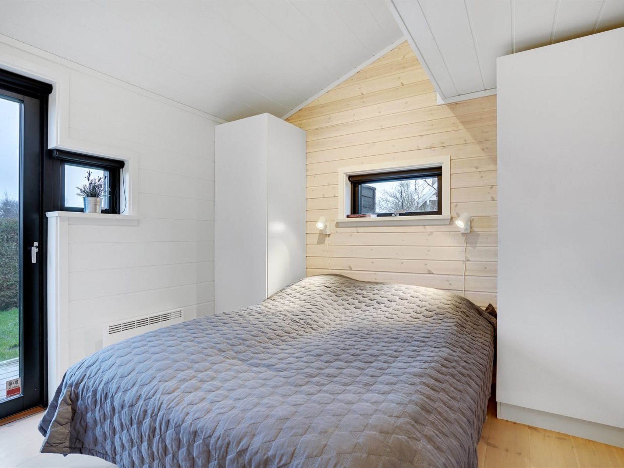 Un dormitorio con cama, ventana y techo de madera.