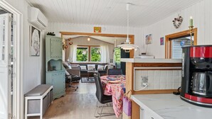 A cozy kitchen with a dining area, wooden ceiling, and a view of greenery outside.