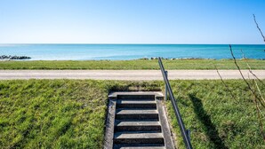 Un escalier en béton mène à une zone herbeuse au bord de la mer.