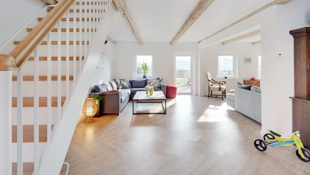 A spacious living area with a wooden staircase, a sofa set, a coffee table, and a view of the outdoors. - "Rouwen" - 1km from the sea by Interhome (Sakskøbing)