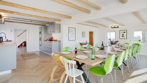 A spacious dining area with a long wooden table, green chairs, and a kitchen in the background. - "Rouwen" - 1km from the sea by Interhome (Sakskøbing)