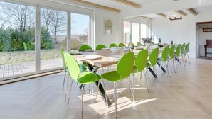 A spacious dining area with a long table and green chairs, large windows, and a view of the outdoors. - "Rouwen" - 1km from the sea by Interhome (Sakskøbing)