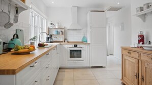 Une cuisine moderne avec des meubles blancs, un plan de travail en bois et un four encastré.