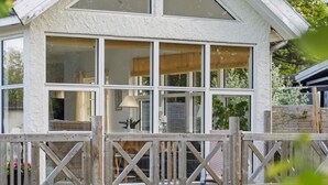 Une maison dotée d’une terrasse en bois et d’une façade blanche.