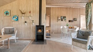 Ett mysigt rum med en vedeldad kamin, möbler i rotting och en matplats.