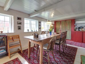 A dining area with a wooden table and chairs, a red patterned rug, and a bookshelf with books. - "Saarah" - 25km from the sea by Interhome (Bredebro)