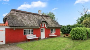 A red cottage with a thatched roof, a white door, and two benches outside. - "Saarah" - 25km from the sea by Interhome (Bredebro)