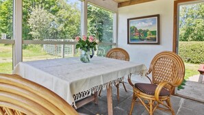 A covered patio with a table and chairs, a vase with flowers, and a painting on the wall. - "Saarah" - 25km from the sea by Interhome (Bredebro)