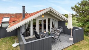 A covered patio with a table and chairs, a white umbrella, and a chimney.