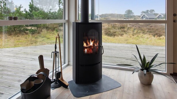 A modern room with a wood-burning stove, wooden flooring, and a view of the outdoors. - "Tiane" - 800m from the sea by Interhome (Fanø)