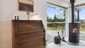 A cozy room with a wooden cabinet, a fireplace, and a window with a view of greenery. - "Tiane" - 800m from the sea by Interhome (Fanø)