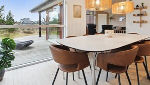 A modern dining area with a large table and brown chairs, a wooden ceiling, and a view through large windows. - "Tiane" - 800m from the sea by Interhome (Fanø)