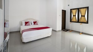 A modern hotel room with a large bed, white walls, and a view of the outside through curtains. - OYO 90595 Ferezsa Kost Syariah (Palembang)