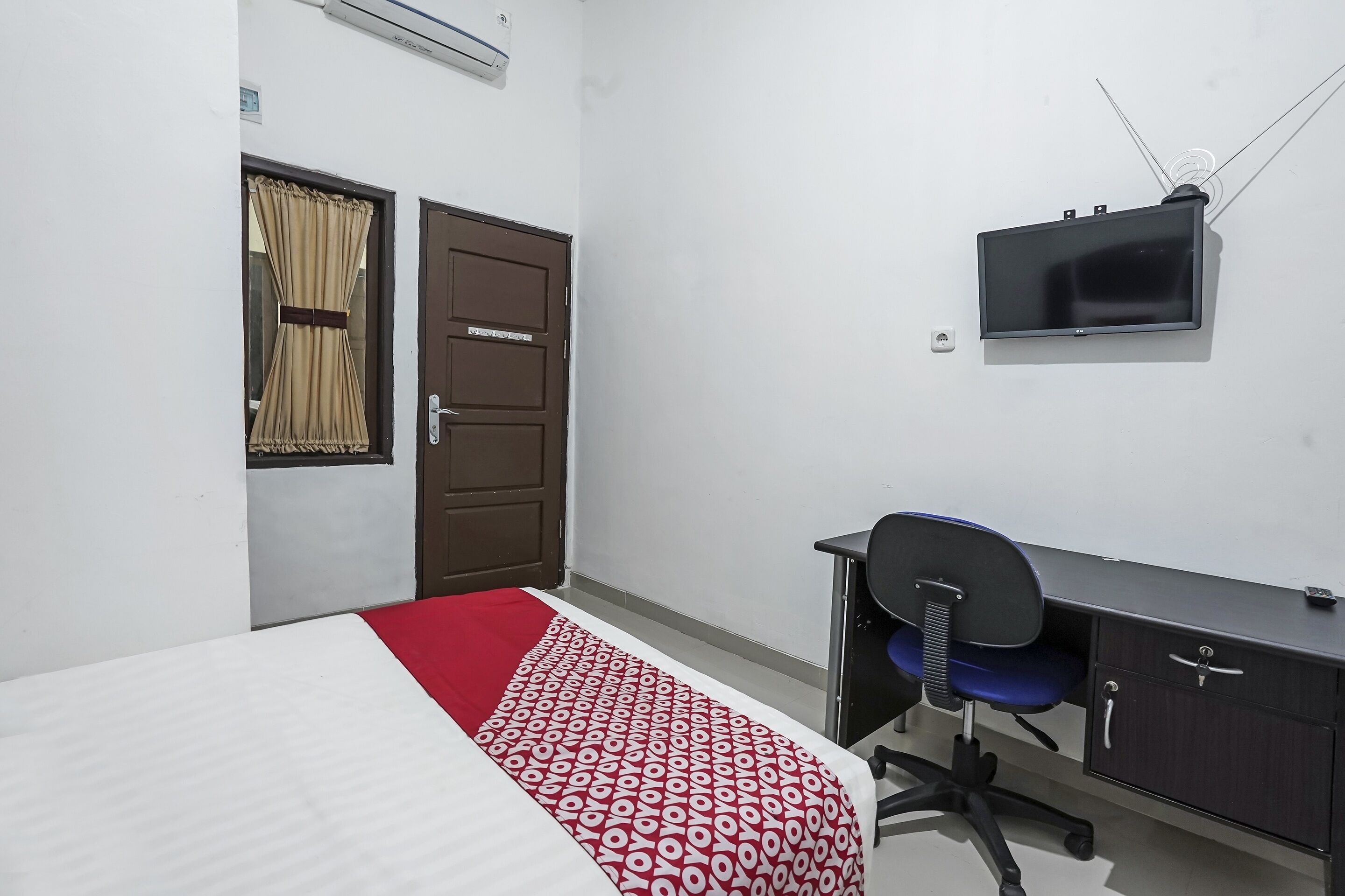 Une chambre à coucher comprenant un lit, un bureau, une chaise, un téléviseur et une armoire.