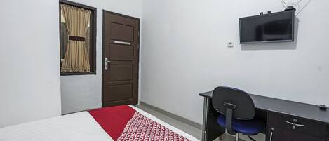 Un dormitorio con cama, escritorio, silla, televisor y armario.
