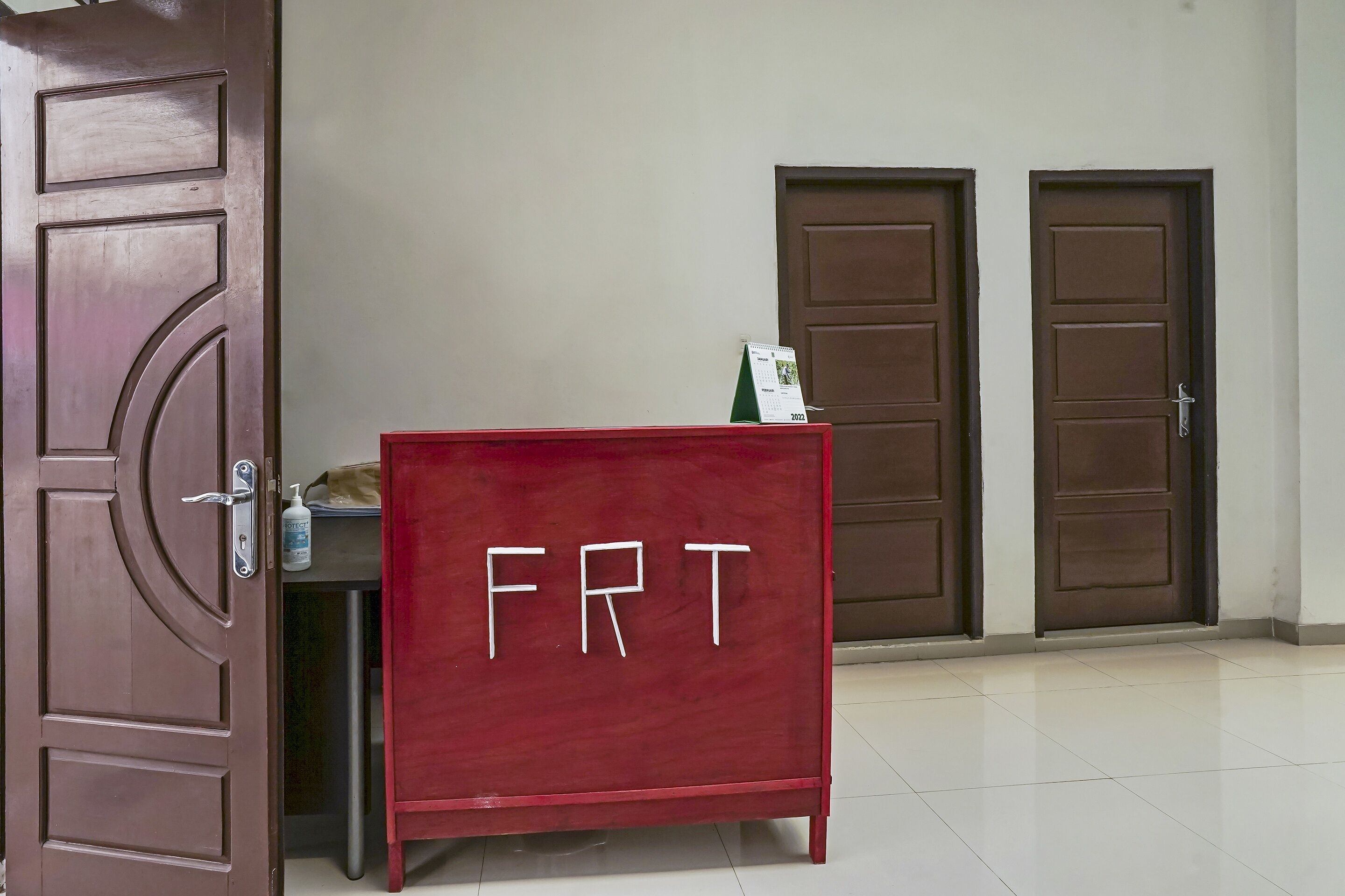 A room with a red cabinet labeled "FRT," a closed door, and a wall calendar.
