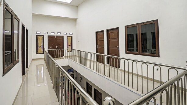A multi-level interior with a polished floor, metal railings, and several doors. - OYO 90595 Ferezsa Kost Syariah (Palembang)