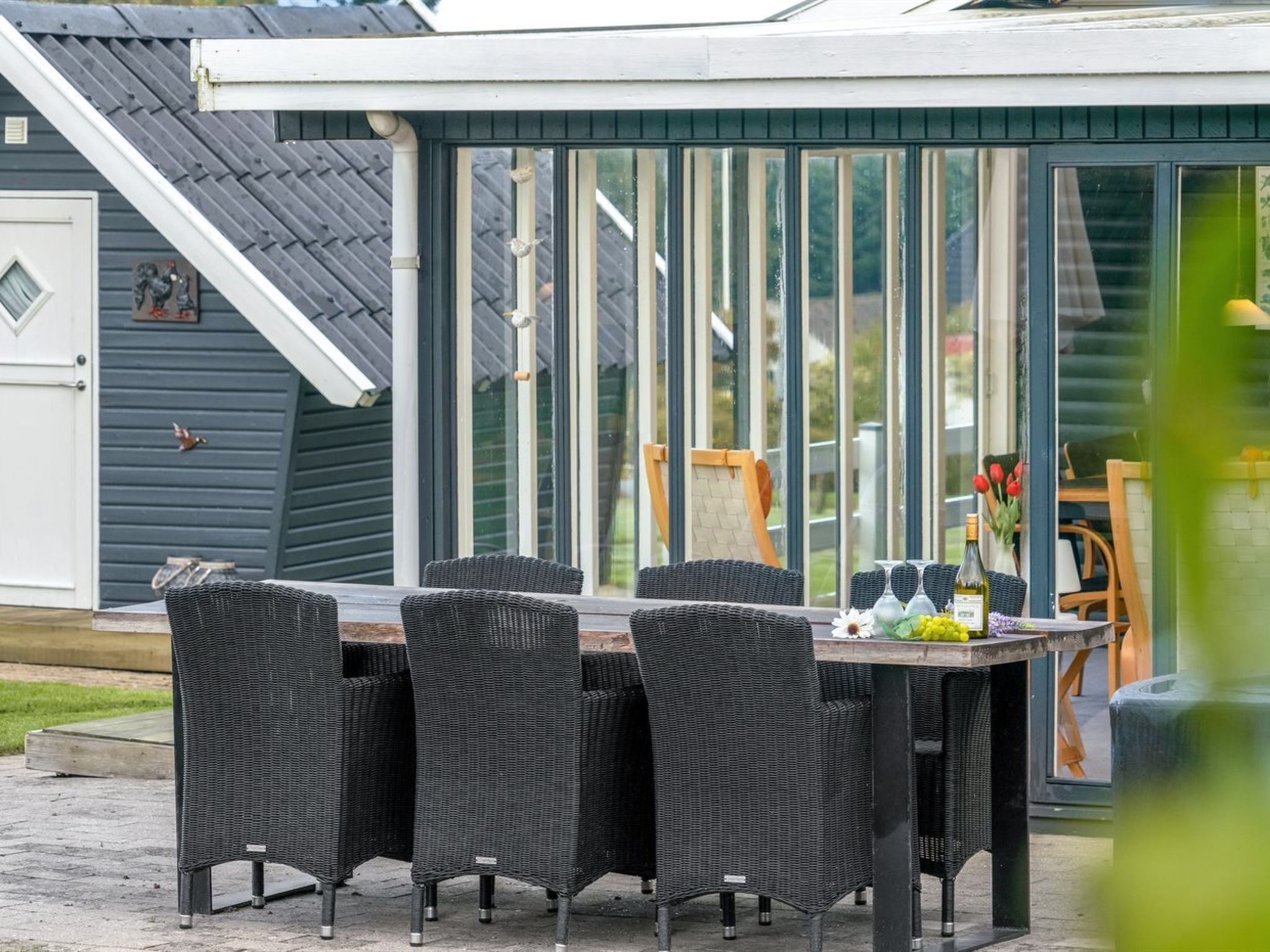 Une terrasse avec une table et des chaises, une porte-fenêtre coulissante et un petit espace extérieur comprenant une chaise et une table.