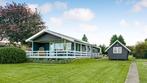 Une maison à deux étages avec un porche couvert et un petit chalet séparé.