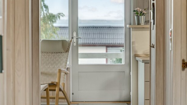 Une pièce avec une porte blanche, une chaise et une étagère sur laquelle est posée une plante en pot.