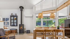 Een ruime woonkamer met een groot raam, een open haard en een eethoek met houten meubels.