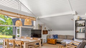 Een ruime woonkamer met een houten eettafel, stoelen, een bank en een boekenkast.
