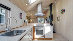 Una cocina moderna con una isla central, pileta de acero inoxidable y horno empotrado.