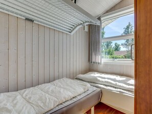 A small, single-bed room with wooden walls and a window.