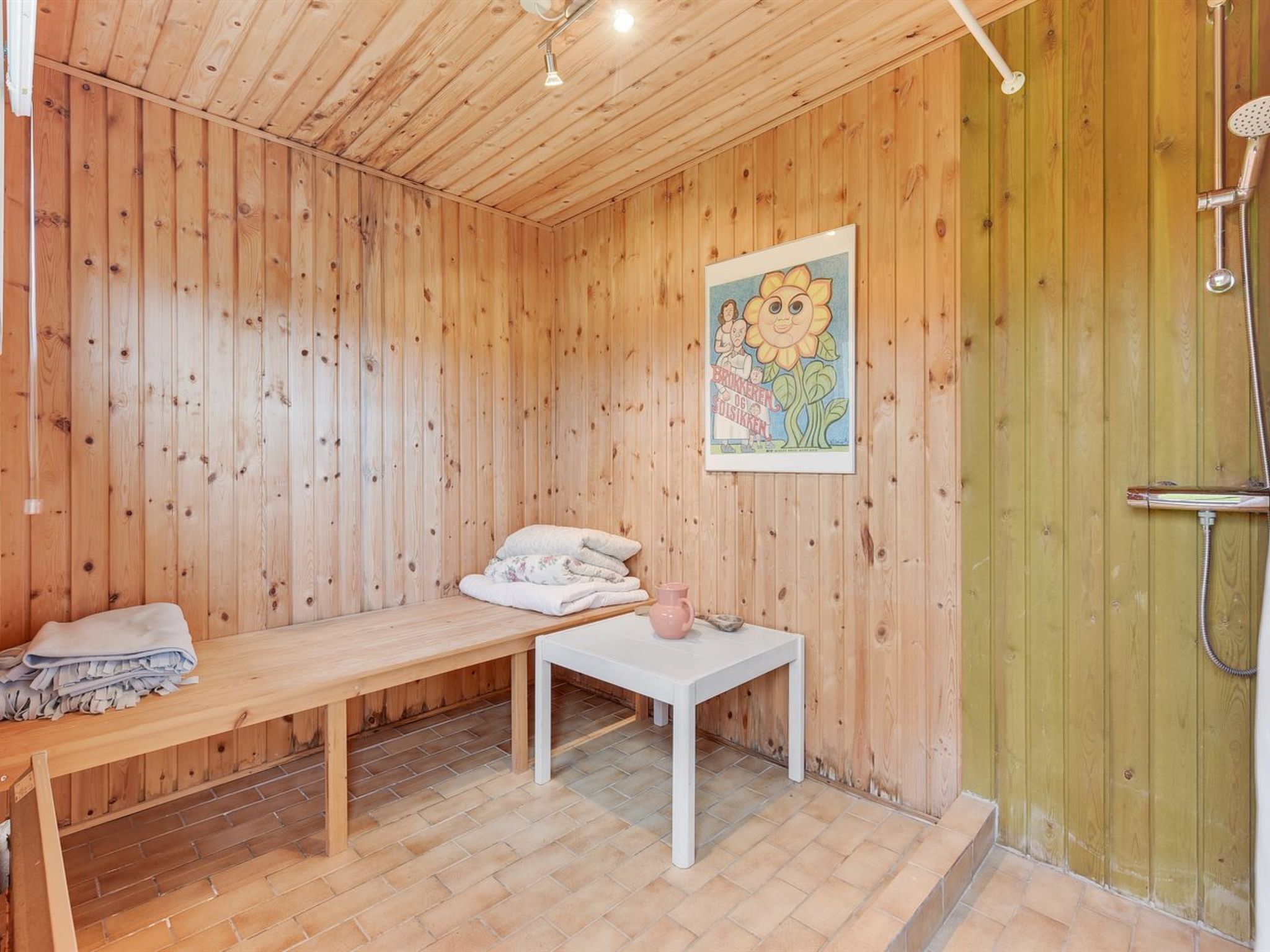 A wooden room with a bench, a small table, and a shower area.