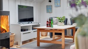 Ein gemütliches Wohnzimmer mit Kamin, Flachbildfernseher, Holztisch und bequemen Sitzgelegenheiten.