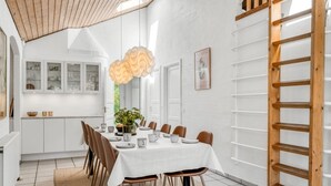 A dining area with a long table, chairs, a chandelier, and a kitchen in the background. - "Anniesette" - 1.5km from the sea by Interhome (Blåvand)