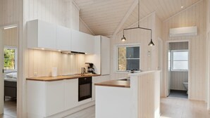 Eine moderne Küche mit weißen Schränken, einer Holz Arbeitsplatte und Pendelleuchten.
