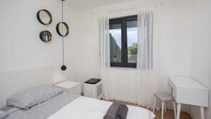 A bedroom with a bed, a desk, a chair, a heater, and a window with curtains. - Mondo Sole in Sveti Bartul (Rasa)