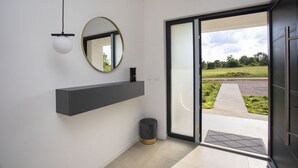 A modern interior with a grey floating shelf, a round mirror, and a black trash bin. - Mondo Sole in Sveti Bartul (Rasa)