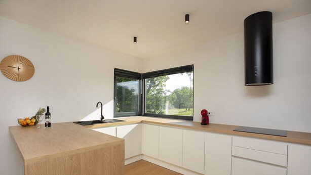 A modern kitchen with a wooden countertop, a built-in sink, and a window providing a view of greenery outside. - Mondo Sole in Sveti Bartul (Rasa)