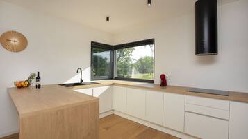Una cocina moderna con encimera de madera, un lavamanos integrado y una ventana que ofrece vistas al verdor exterior.