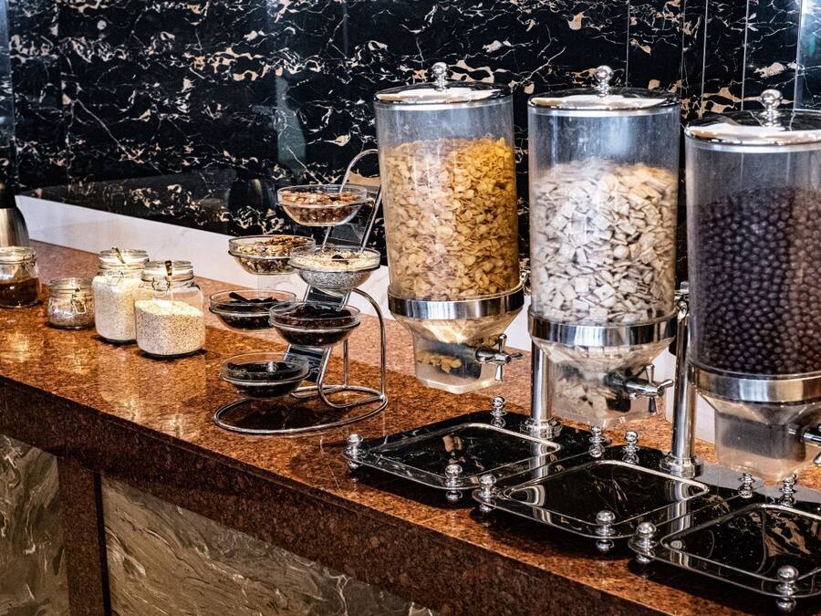 Montaje de bufé con diferentes recipientes de comida y una máquina de café sobre una encimera de mármol.