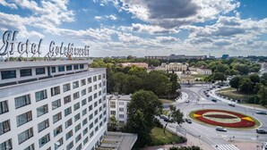 Un hôtel à la façade moderne, un carrefour avec une circulation importante et des espaces verts environnants.