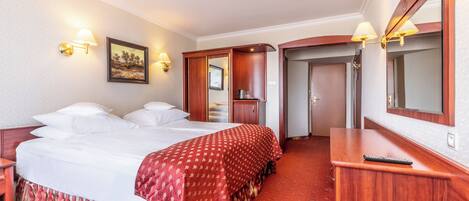 A hotel room with a large bed, a desk, and a mirror.