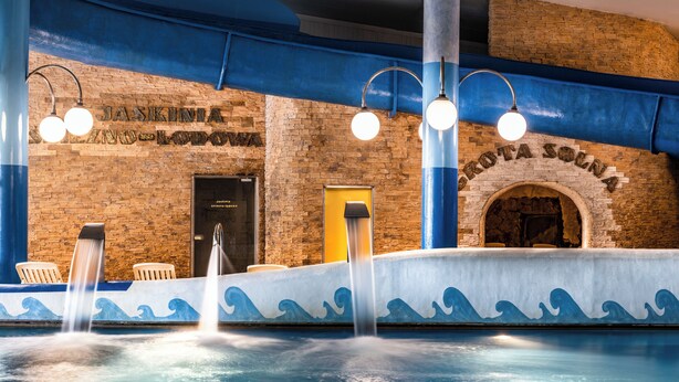 Un espace piscine agrémenté d’un mur en briques, d’un motif ondulé bleu et d’un panneau indiquant : « JASKINIA ZIMNO LODOPO ».