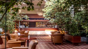 Un espace bar doté d’un comptoir en bois, de différents types de sièges, notamment des canapés et des tables rondes, et d’une variété de bouteilles exposées sur des étagères derrière le bar.